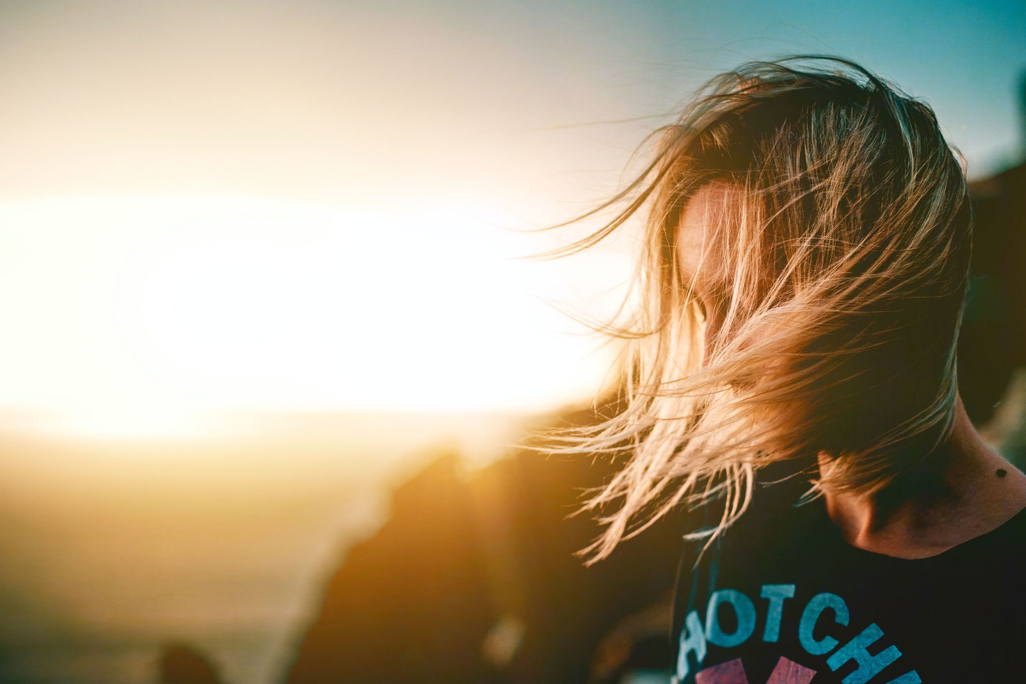 Une femme sur le premier plan et en fond un couché de soleil 