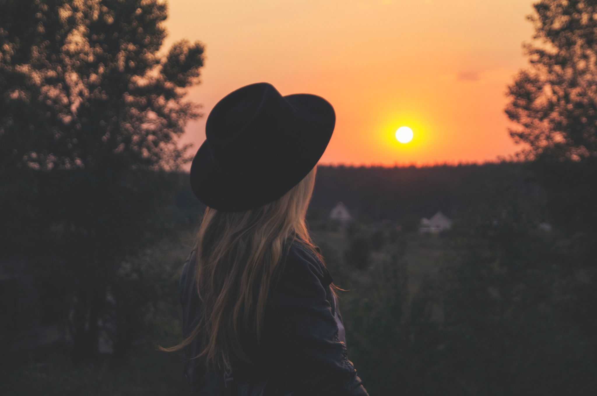 Une femme sur le premier plan et en fond un couché de soleil 