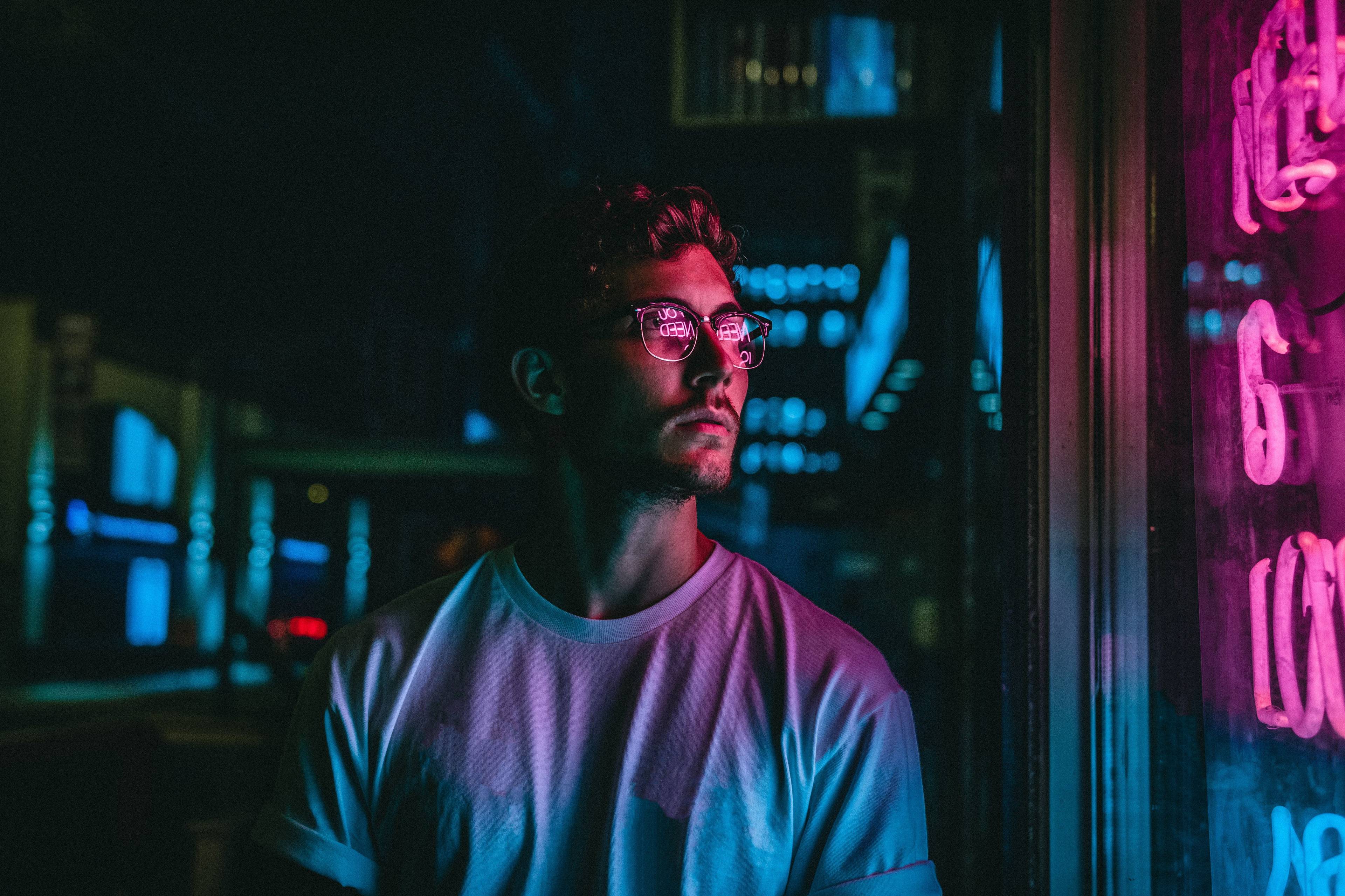 Photo homme qui regarde un néon dans la nuit 
